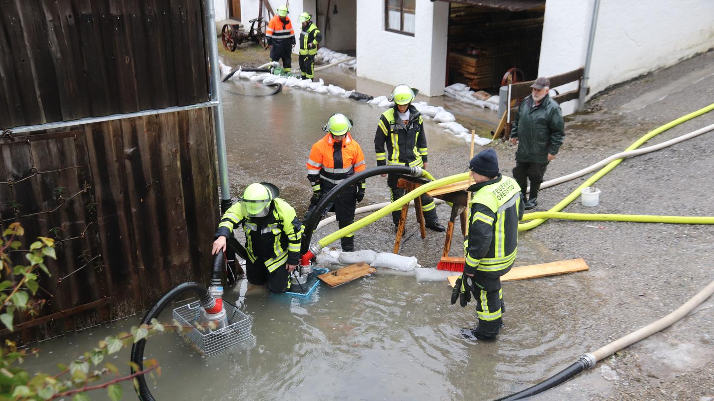 An einem Haus bei Oberstdorf pumpen Feuerwehrleute Wasser ab. Die Überschwemmungsgefahr verlagert sich nun von der Alpenregion nach Nordbayern.