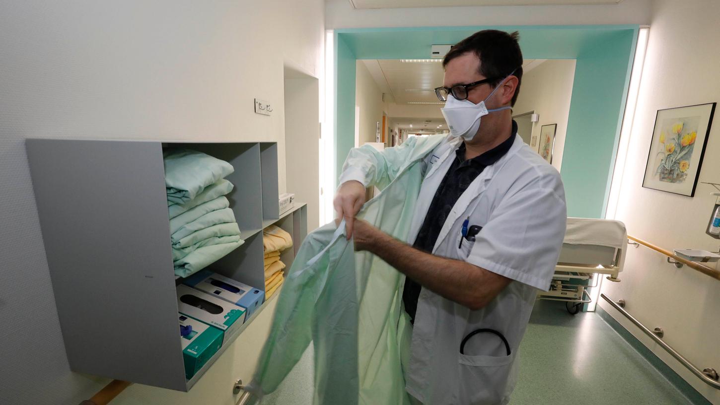 Oberarzt Dr. Jochen Böhm legt die Schutzkleidung an, ehe er  das Patientenzimmer  betritt.