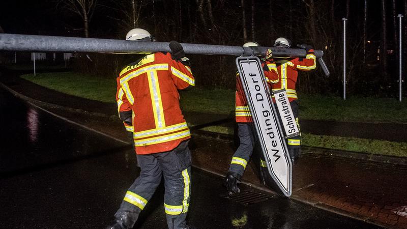 Schleswig-Holstein, Handewitt: Feuerwehrleute tragen eine Straßenlaterne von der Straße, die zuvor von Orkanböen des Sturmtiefs «Sabine» umgeweht und dann demontiert worden war. Foto: Benjamin Nolte/dpa +++ dpa-Bildfunk +++
