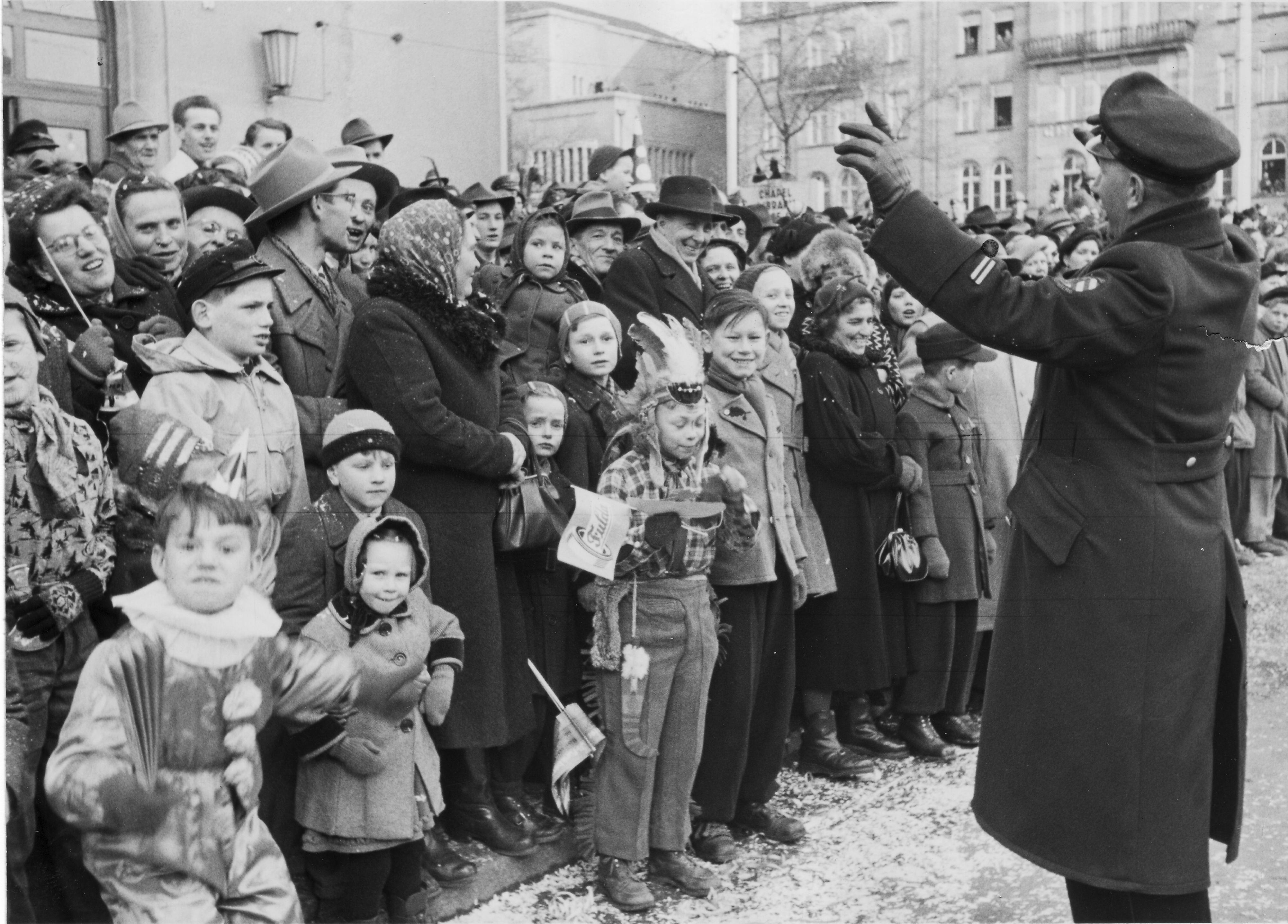 Ordnung muss sein: beim Faschingszug 1953 dirigiert ein Polizist die Menschenmenge am Straßenrand.