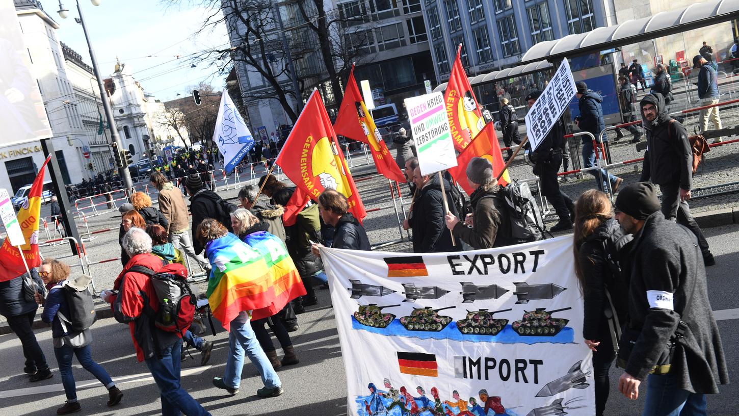 Teilnehmer der Demonstration des "Aktionsbündnis gegen die Nato-Sicherheitskonferenz" ziehen an den Absperrungen vorbei, die zum Hotel Bayerischer Hof führen.