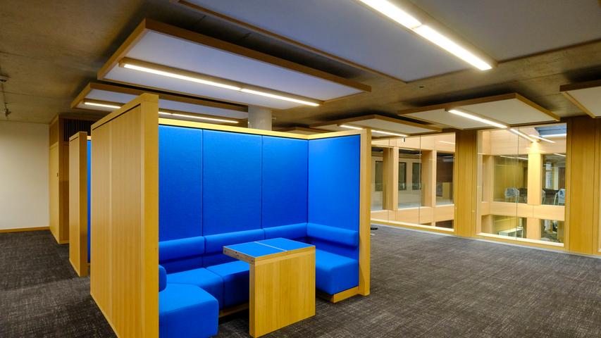 In den Großraumbüros gibt es Ruhe- oder Besprechungszonen, deren Möbel in kräftigen Farben – wie hier in Blau – gehalten sind.