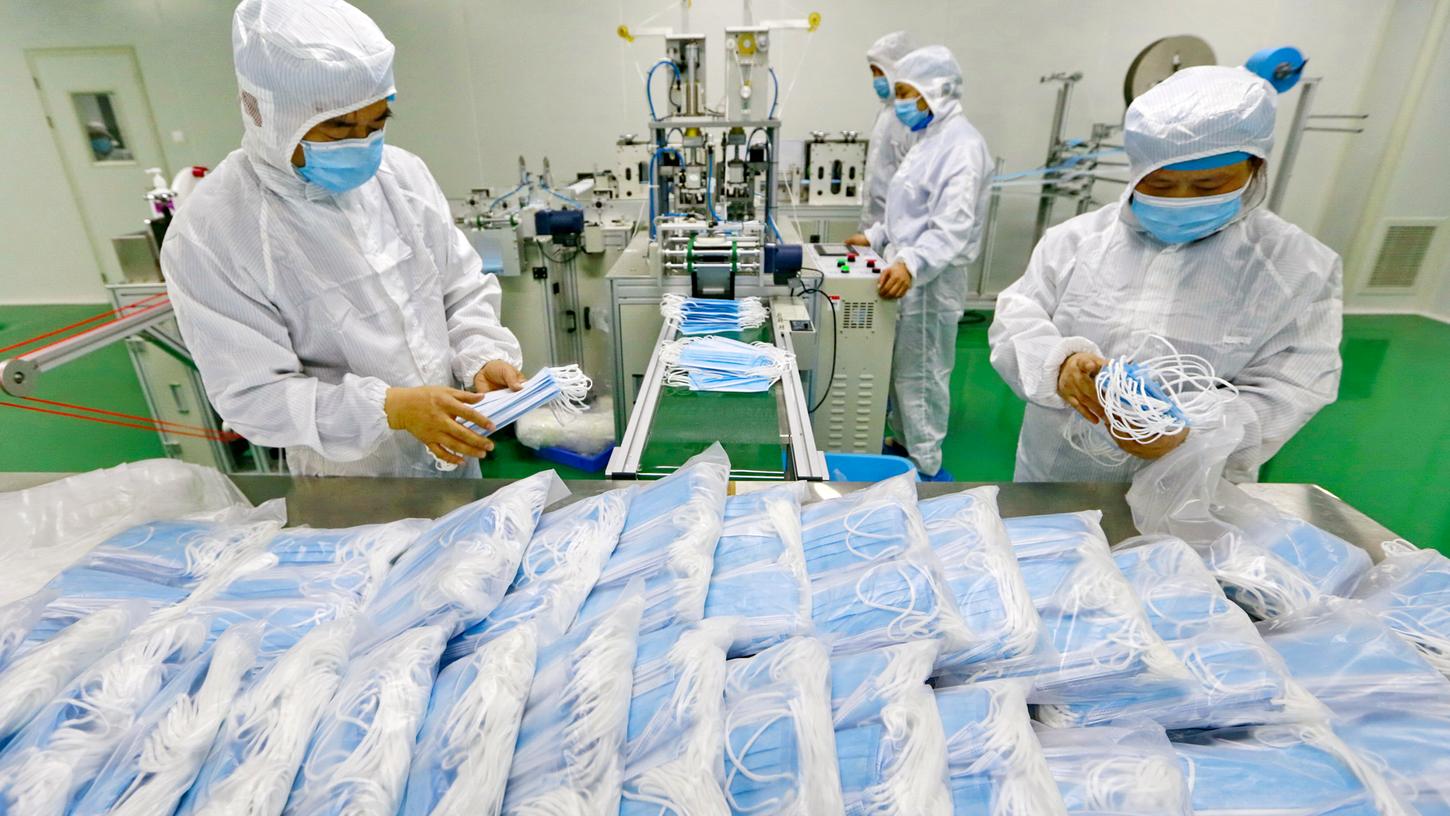 China, Suining: Arbeiter in einer Fabrik packen Schutzmasken ein. Die Zahl neuer Infektionen ist in China erneut gestiegen.