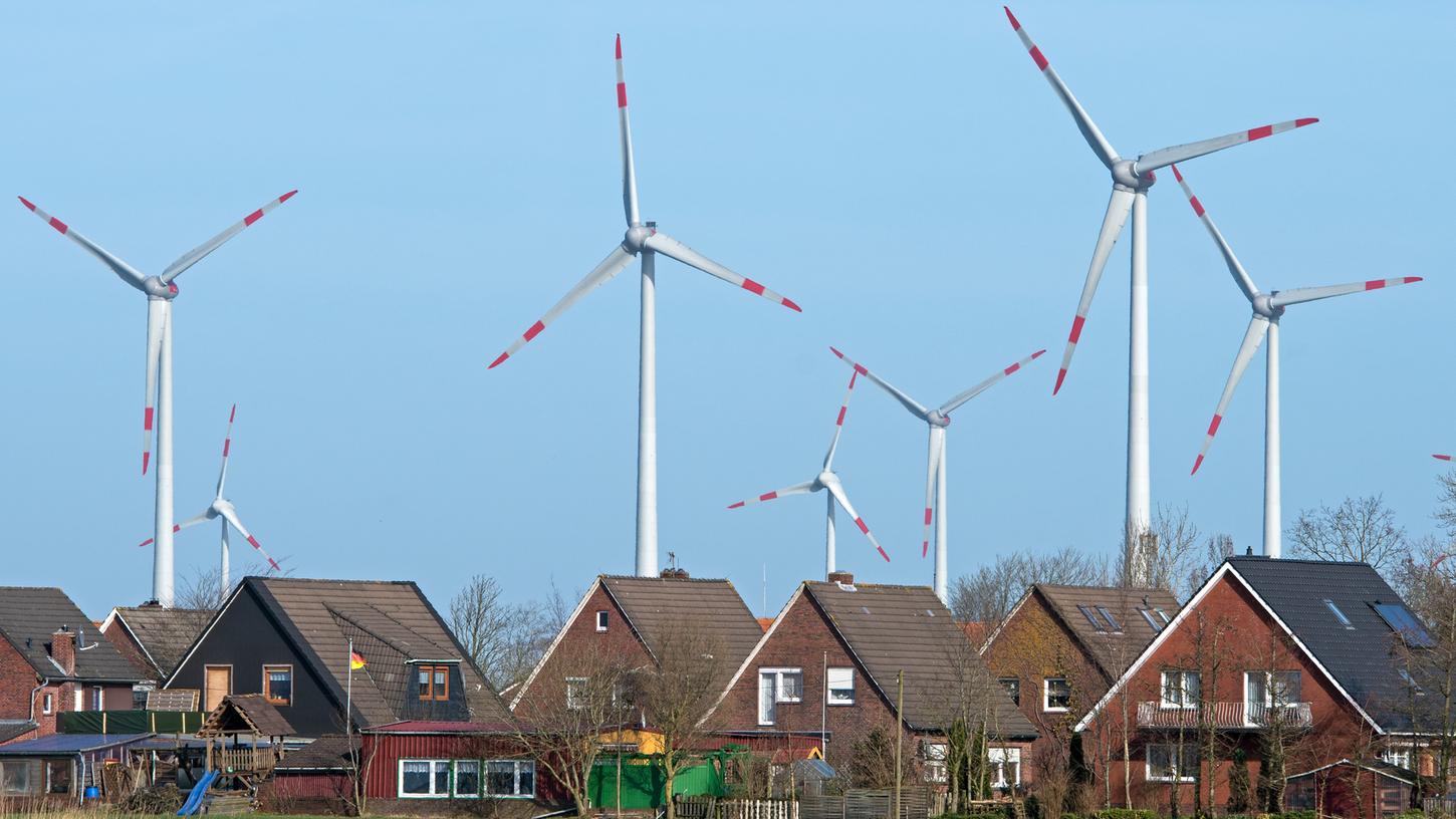 Niedersachsen, Wittmund: Windräder eines Windparks drehen sich dicht hinter einer Wohnsiedlung.