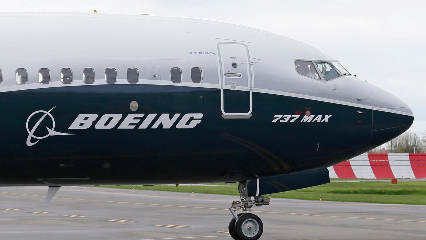 Ein Pilot winkt aus der Pilotenkabine eines Flugzeuges vom Typ Boeing 737 Max. Knapp ein Jahr nach dem zweiten Absturz einer Boeing 737 Max binnen weniger Monate hat ein Untersuchungsausschuss des US-Kongresses schwere Vorwürfe erhoben.