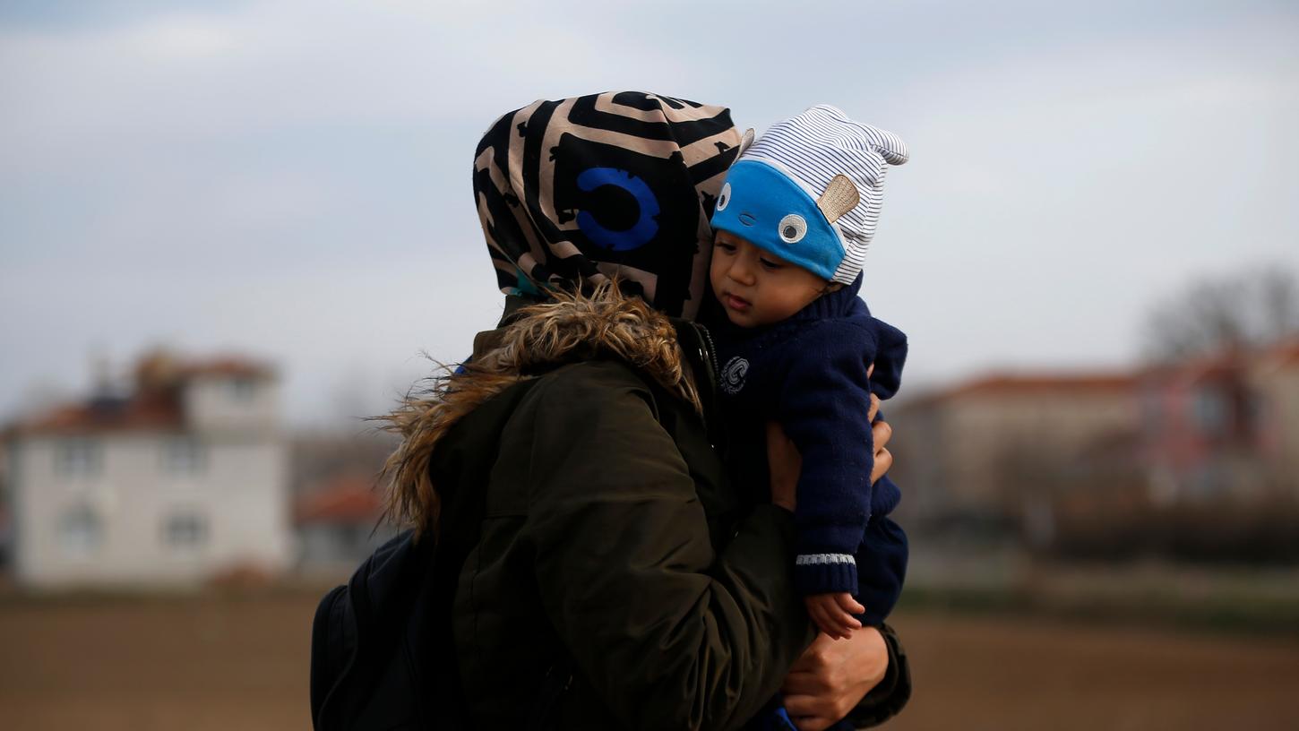 Eine Migrantin trägt ihr Kind in der Nähe der türkisch-griechischen Grenze. Nachdem die Türkei Anfang März ihre Grenzen für offen erklärt hat, versuchen Tausende Flüchtlinge und Migranten ins EU-Land Griechenland zu kommen.