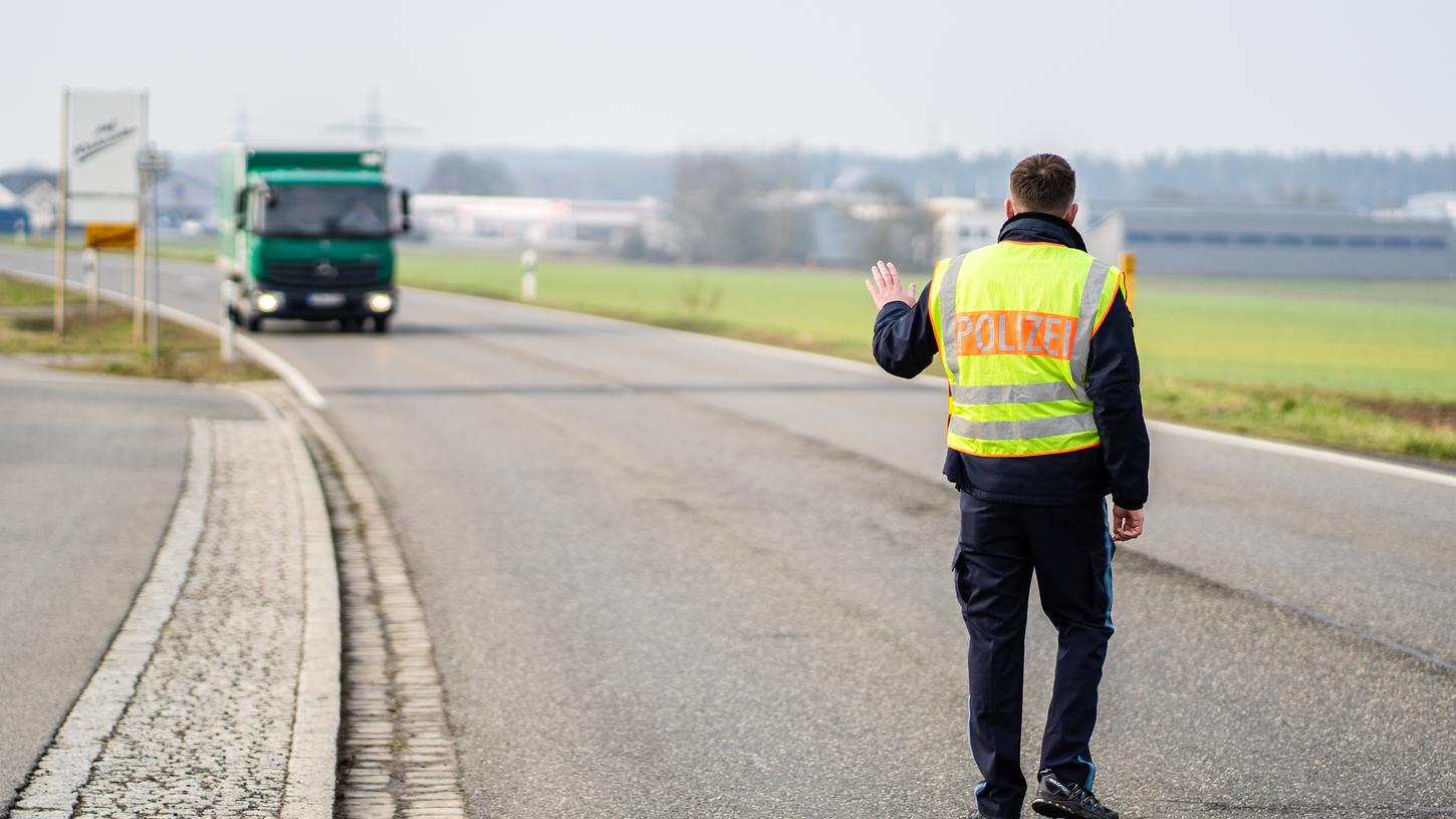 Ein Polizist hält bei der Ortseinfahrt von Mitterteich einen LKW an. Das Landratsamt in Tirschenreuth erteilte am Mittwochabend eine Ausgangssperre, weil in Mitterteich die Zahl der am Coronavirus erkrankten Menschen besonders hoch ist.