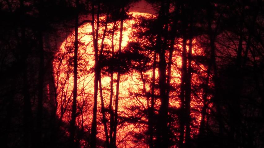 Nein, das ist kein Blick in die Glut eines Feuers. Hier wurde der Sonnenuntergang in Oberasbach per Teleobjektiv fotografiert. Die Sonne stand genau hinter einem Wäldchen.