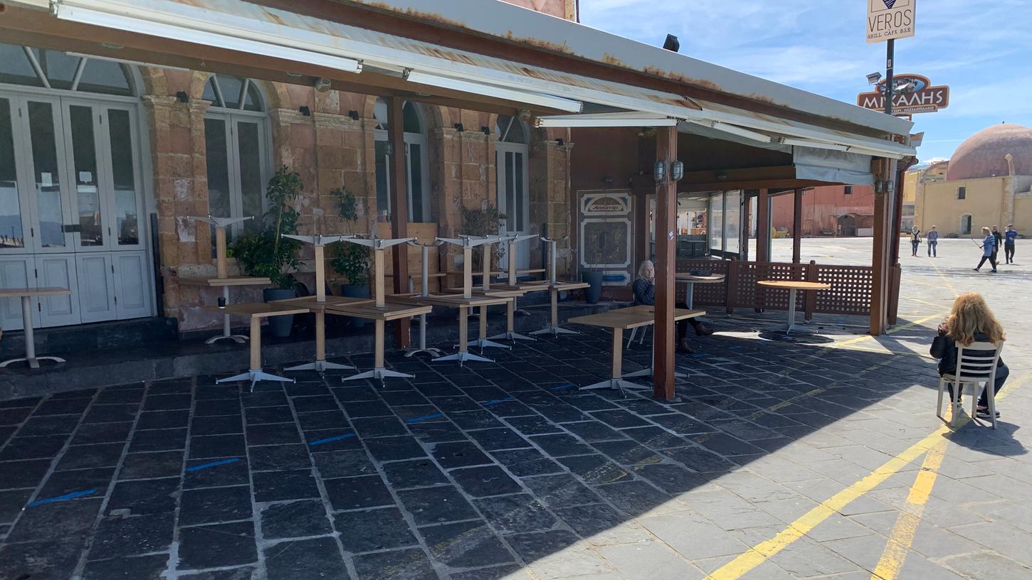 Alle Stühle sind an einem warmen und sonnigen Samstagnachmittag bei diesem Lokal an der Strandpromenade in Chania hochgestellt, die Chefin hat sich ein Plätzchen in der Sonne gesichert.