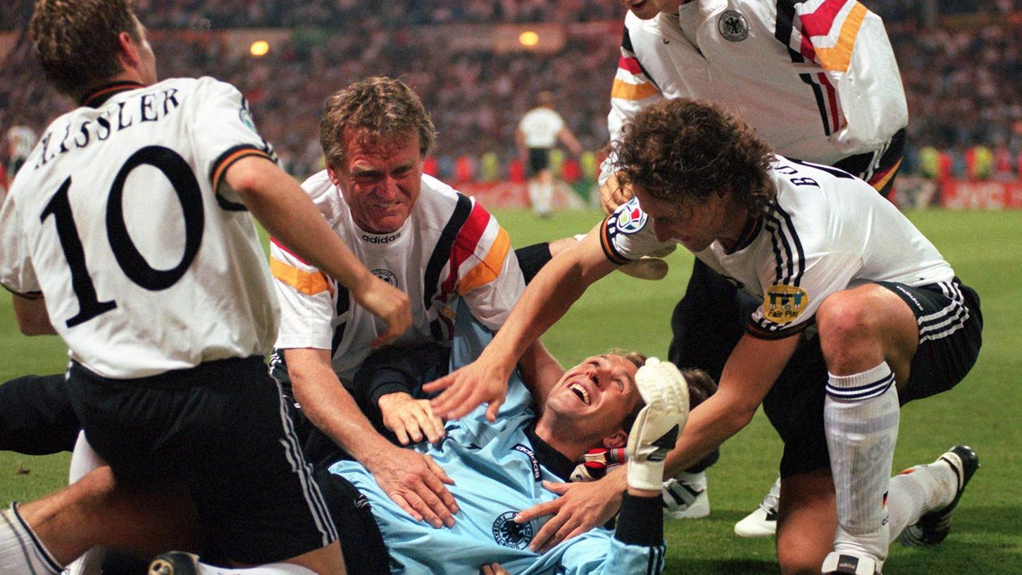 Von seinen Mannschaftskameraden Thomas Häßler (l), Marko Bode (r), Fredi Bobic (dahinter) und Torwart-Trainer Sepp Maier (2.v.l.) umjubelt, liegt der deutsche Torwart Andreas Köpke nach dem 6:5-Sieg im Elfmeterschießen beim Halbfinalspiel der Fußball-Europameisterschaft EURO '96 zwischen Deutschland und England auf dem Rasen des Londoner Wembley-Stadions. Von seinen Mannschaftskameraden Thomas Häßler (l), Marko Bode (r), Fredi Bobic (dahinter) und Torwart-Trainer Sepp Maier (2.v.l.) umjubelt, liegt der deutsche Torwart Andreas Köpke nach dem 6:5-Sieg im Elfmeterschießen beim Halbfinalspiel der Fußball-Europameisterschaft EURO '96 zwischen Deutschland und England auf dem Rasen des Londoner Wembley-Stadions.
