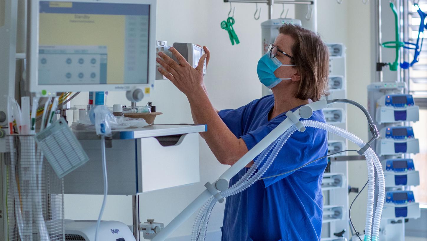 Eine Krankenschwester prüft ein Beatmungsgerät in einem Zimmer auf einer Intensivstation.