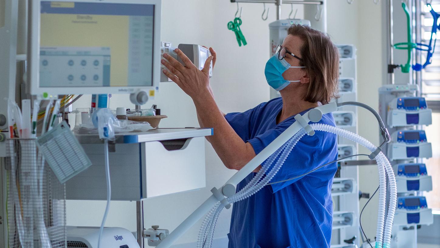 Eine Krankenschwester prüft ein Beatmungsgerät in einem Zimmer auf einer Intensivstation. Eine Krankenschwester prüft ein Beatmungsgerät in einem Zimmer auf einer Intensivstation.